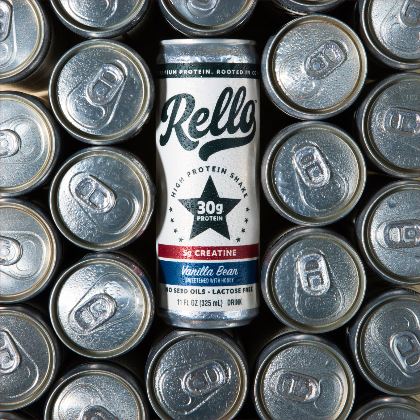 Front view of Rello Vanilla Protein Shake can showing 30g protein star and 5g creatine label amid surrounding aluminum can tops