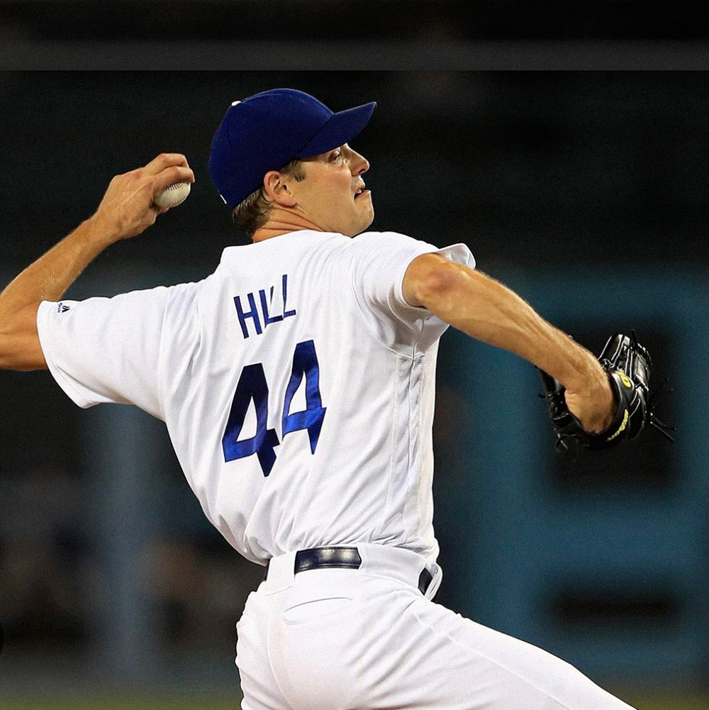 Baseball pitcher winding up to throw a pitch on a stadium field at night