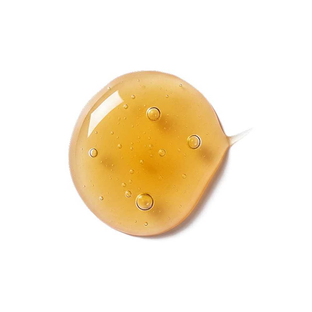 Top-down view of organic honey droplet showcasing golden color and air bubbles on white background